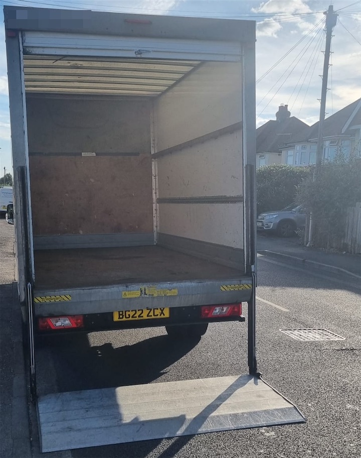 The open back of a Luton van with its tail lift lowered to the road
