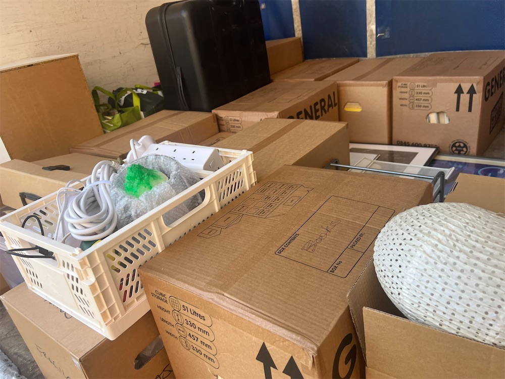 The back of a van packed with moving boxes and a suitcase